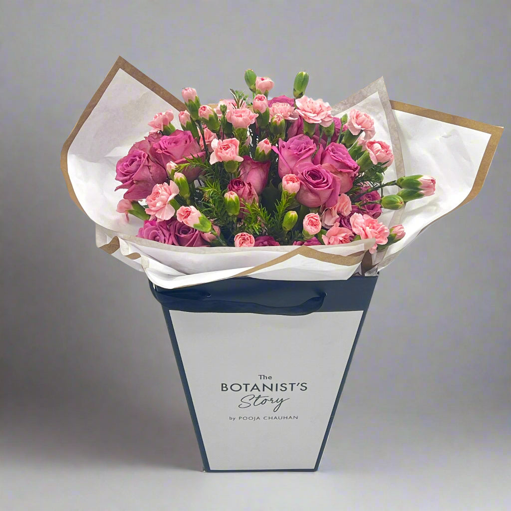 Bouquet of pink flowers in a white box with 'The Botanist's Story' branding on a white background